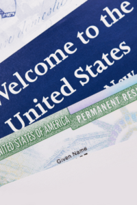 A close-up of a U.S. permanent resident card partially overlapping a "Welcome to the United States" document.